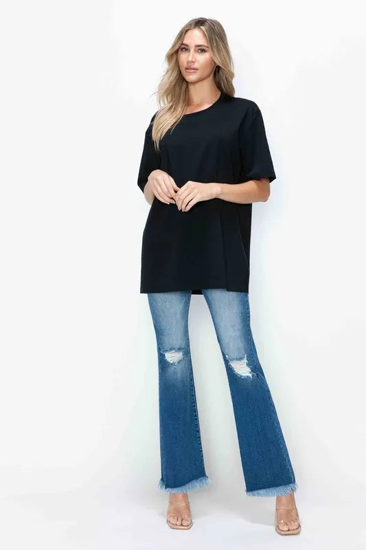 Woman wearing a black top and blue jeans on a white background