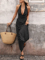 Woman in a black polka dot dress holding a straw bag against a textured wall.