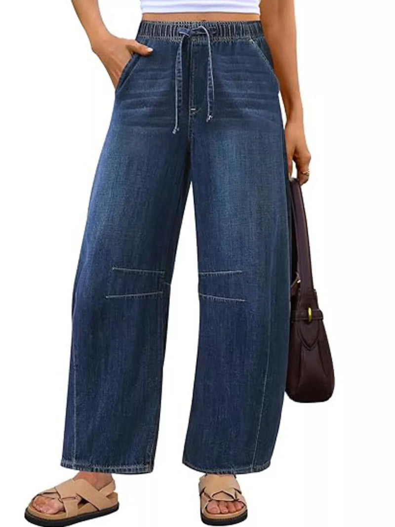 Person wearing wide-leg blue jeans on a white background