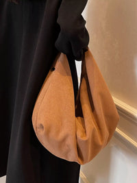 Person holding a brown handbag indoors