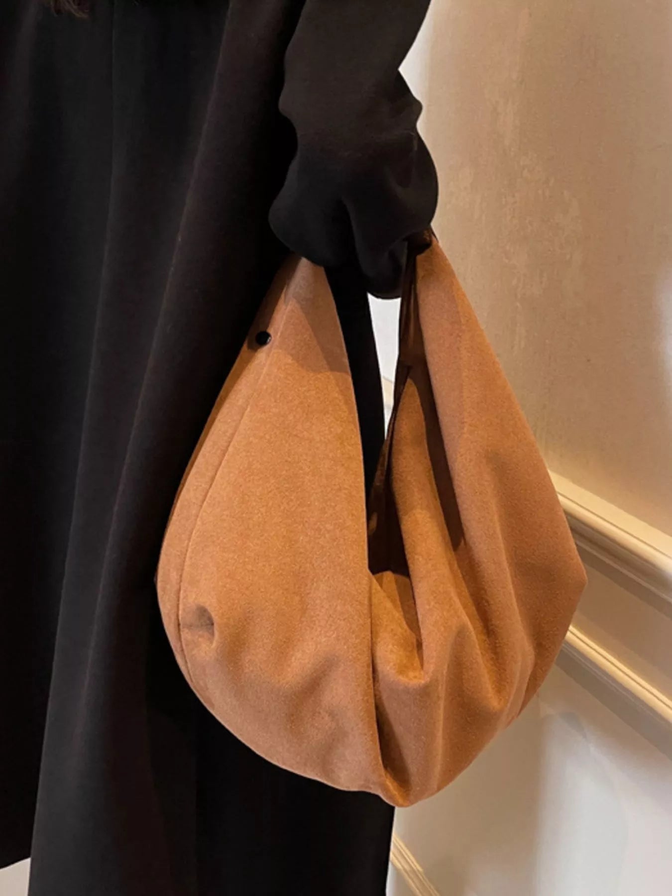 Person holding a brown handbag indoors