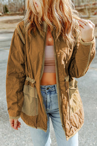 Person wearing a brown jacket, white top, and blue jeans outdoors.