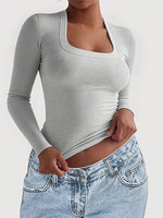 Gray long-sleeve top worn by a person on a white background