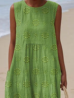 Green dress with floral patterns worn by a person on a beach.