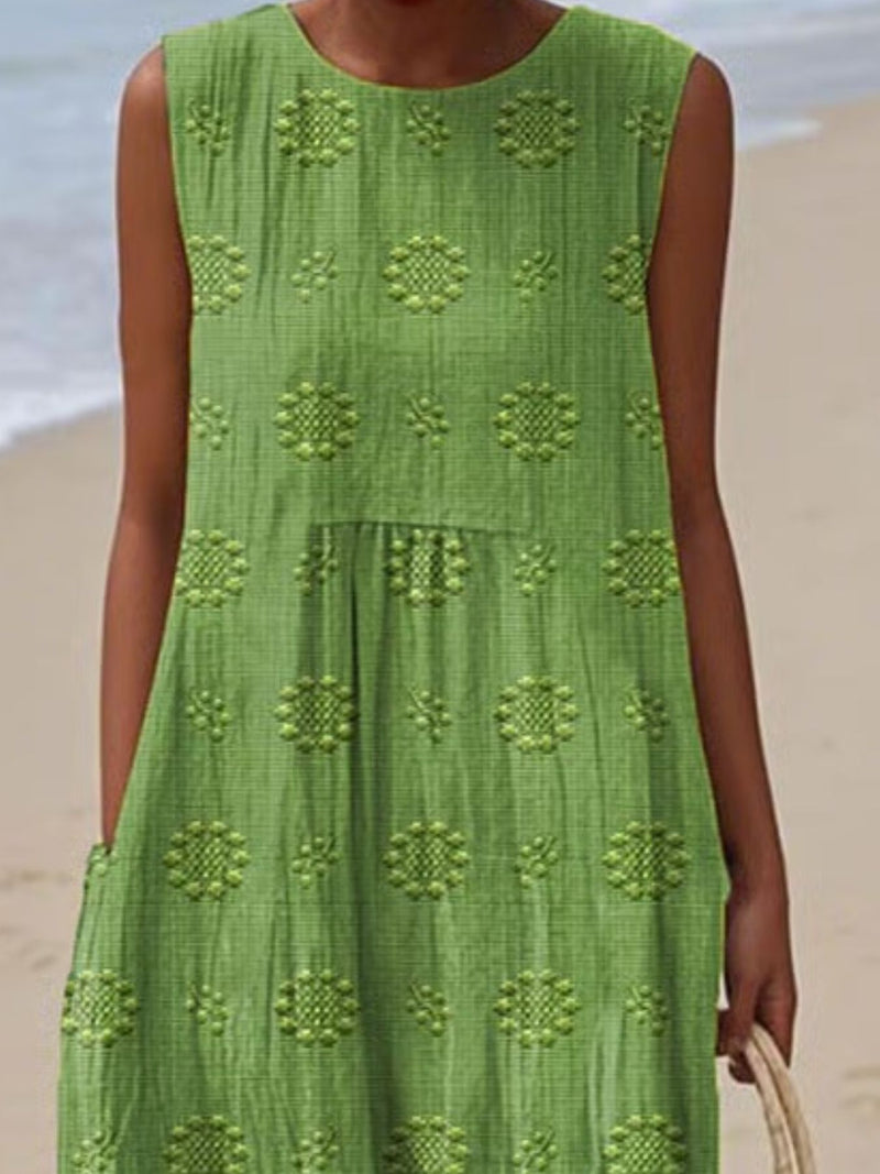 Green dress with floral patterns worn by a person on a beach.