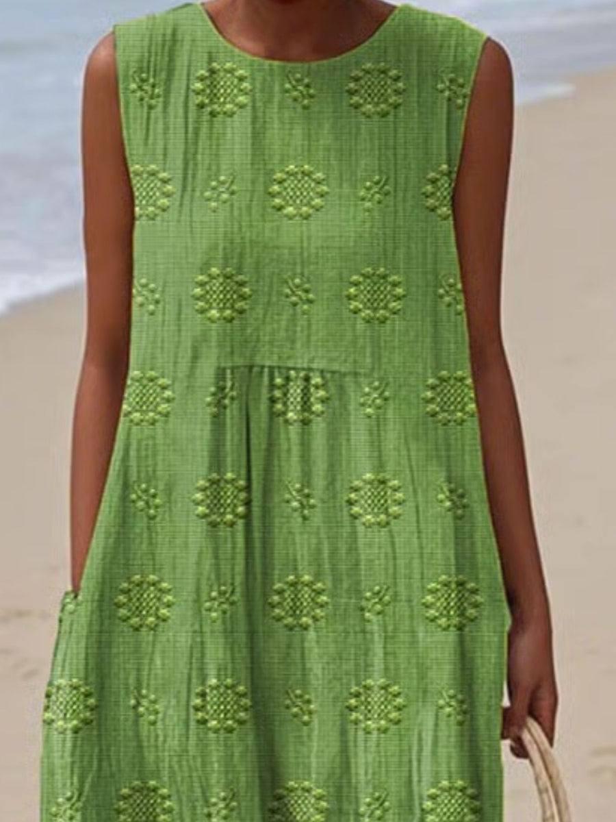 Green dress with floral patterns worn by a person on a beach.