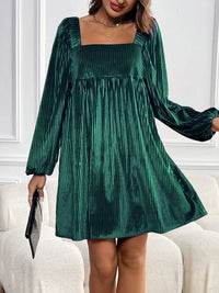 Green velvet dress worn by a person on a white couch