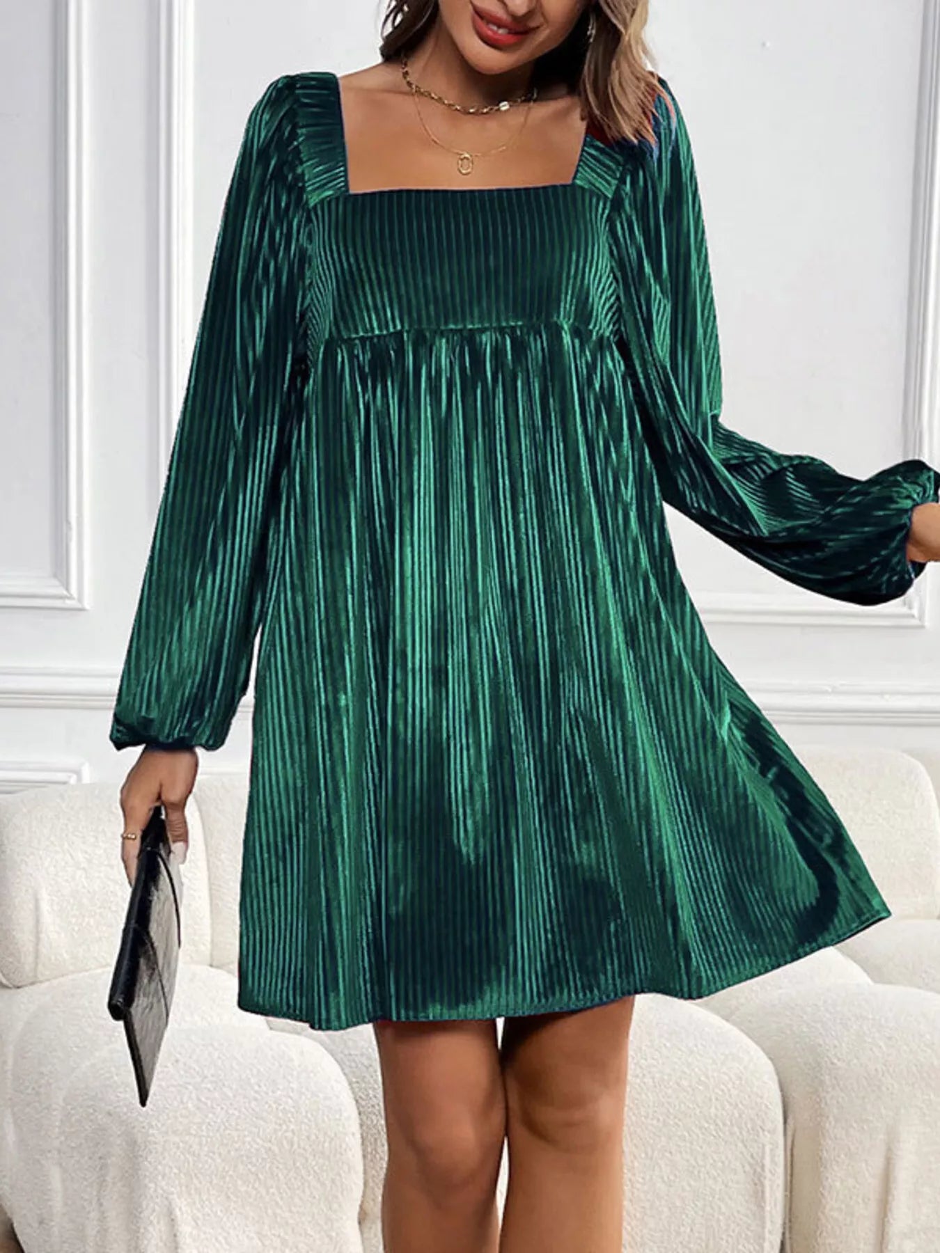 Green velvet dress worn by a person on a white couch