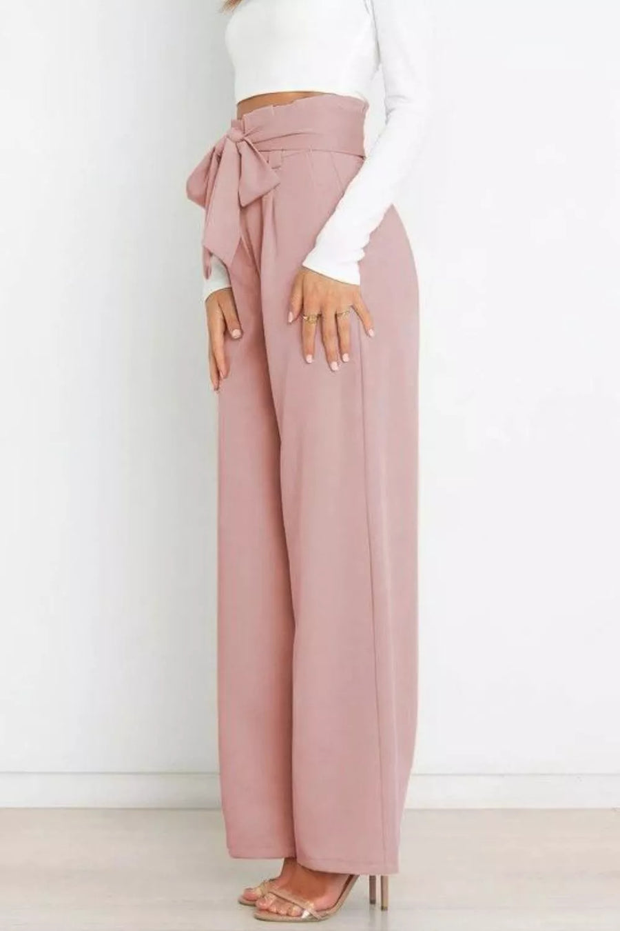 Person wearing pink wide-leg pants with a white top against a white background
