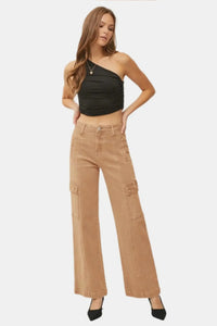 Woman wearing tan cargo pants and a black top on a white background