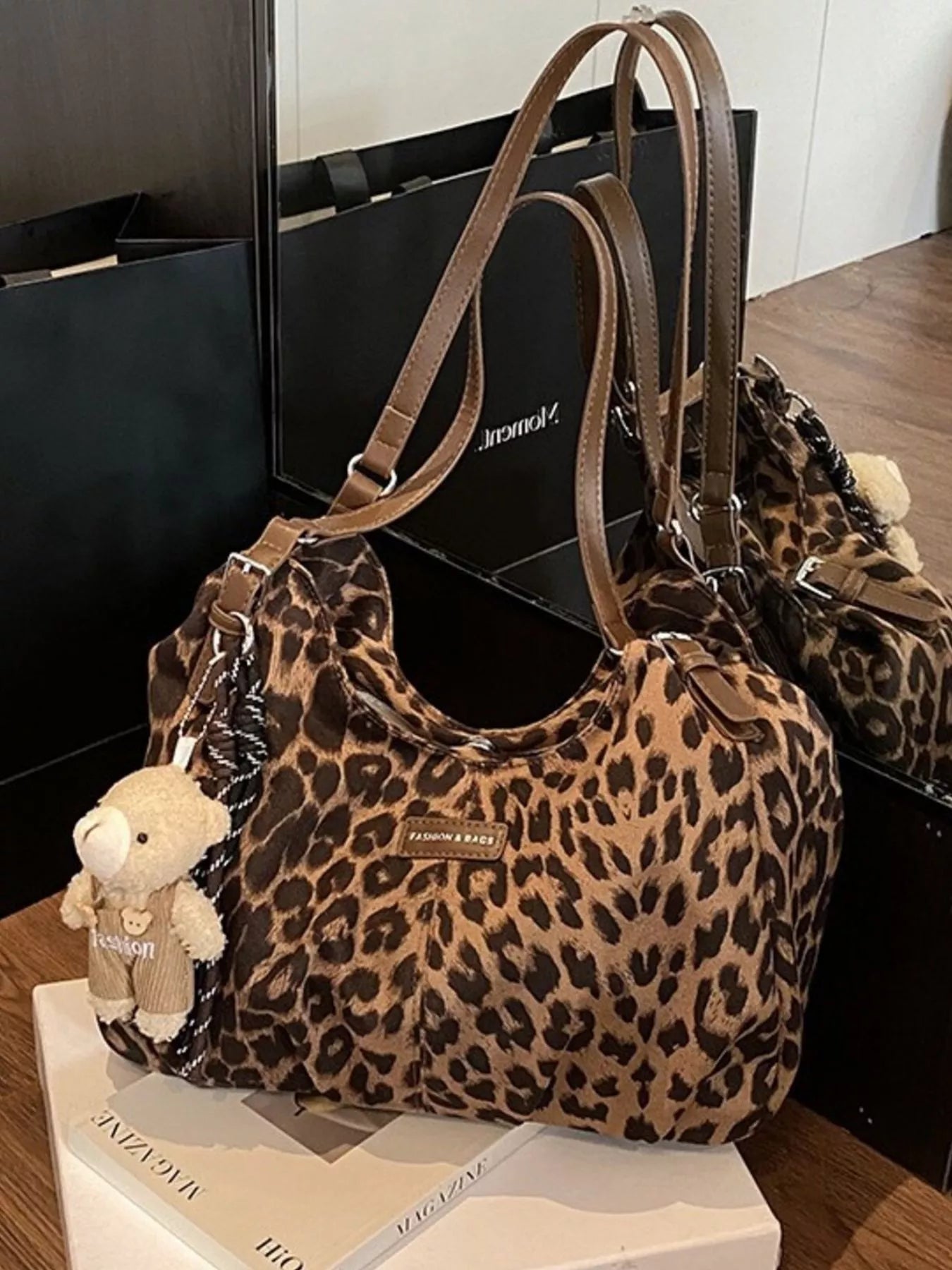 Leopard print handbag with a teddy bear charm on a magazine