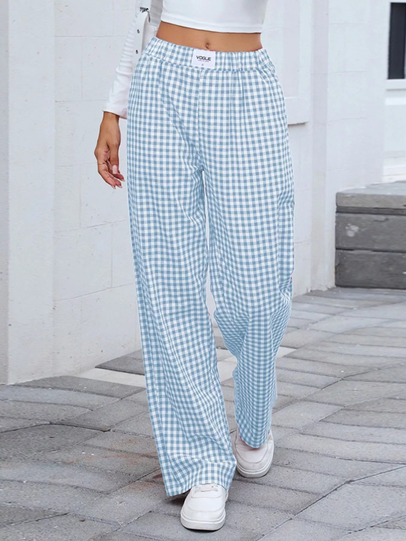 Person wearing blue and white checkered pants on a stone pavement.