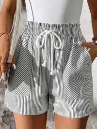 Person wearing striped shorts with a drawstring waist against a neutral background