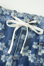 Close-up of blue floral denim shorts with white drawstring.