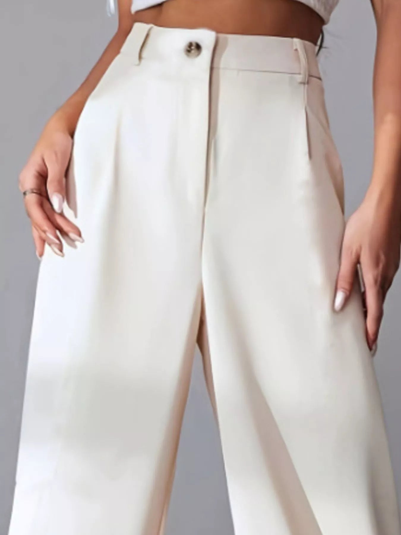 White pants with a high waist and front slit on a gray background