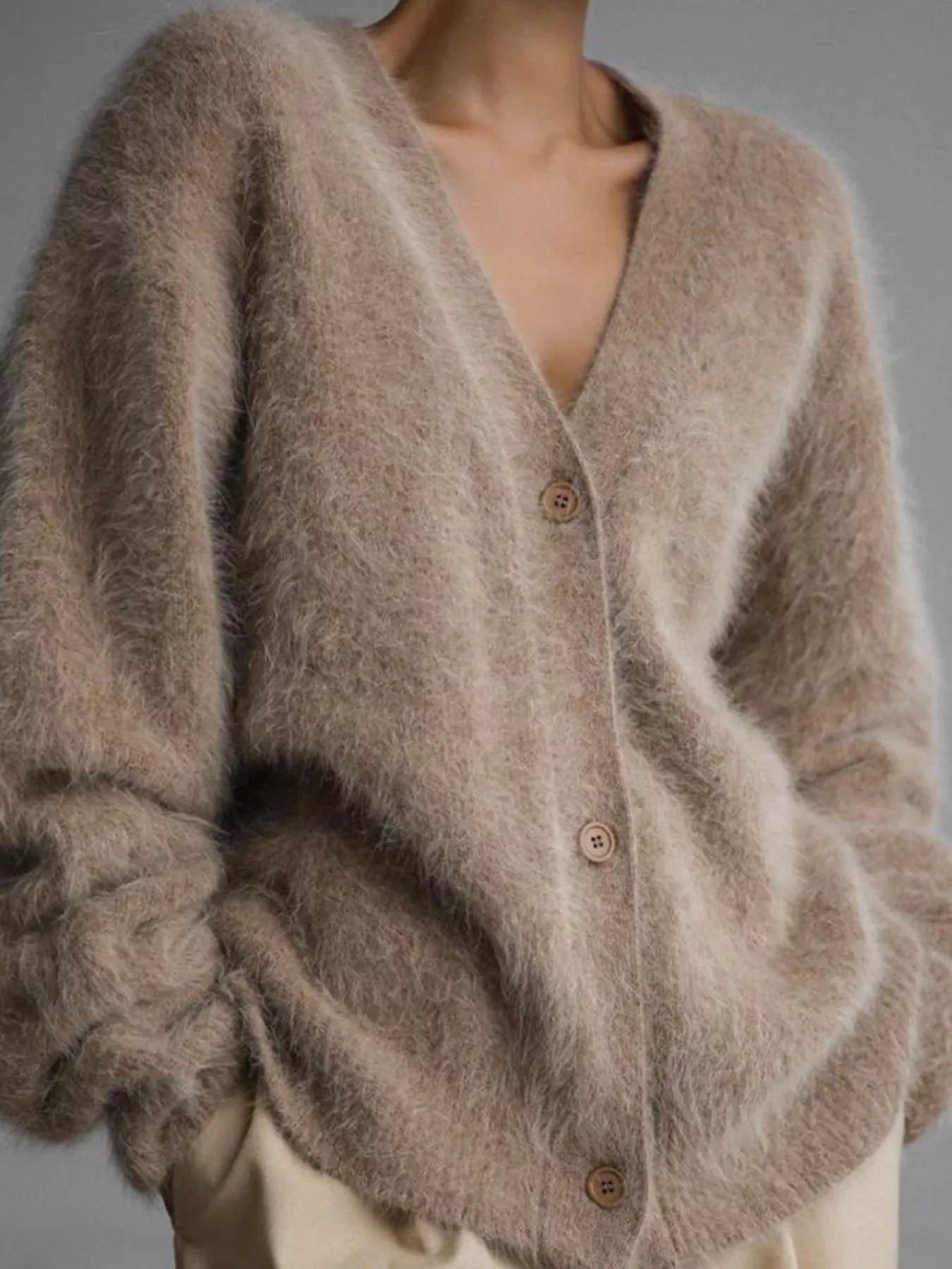 Close-up of a fluffy brown cardigan with buttons on a neutral background