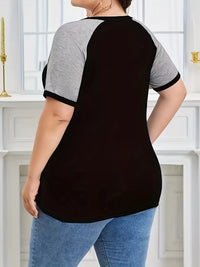 Person wearing a black and gray baseball-style shirt with blue jeans indoors.