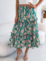 Person wearing a green floral skirt sitting on a white chair.