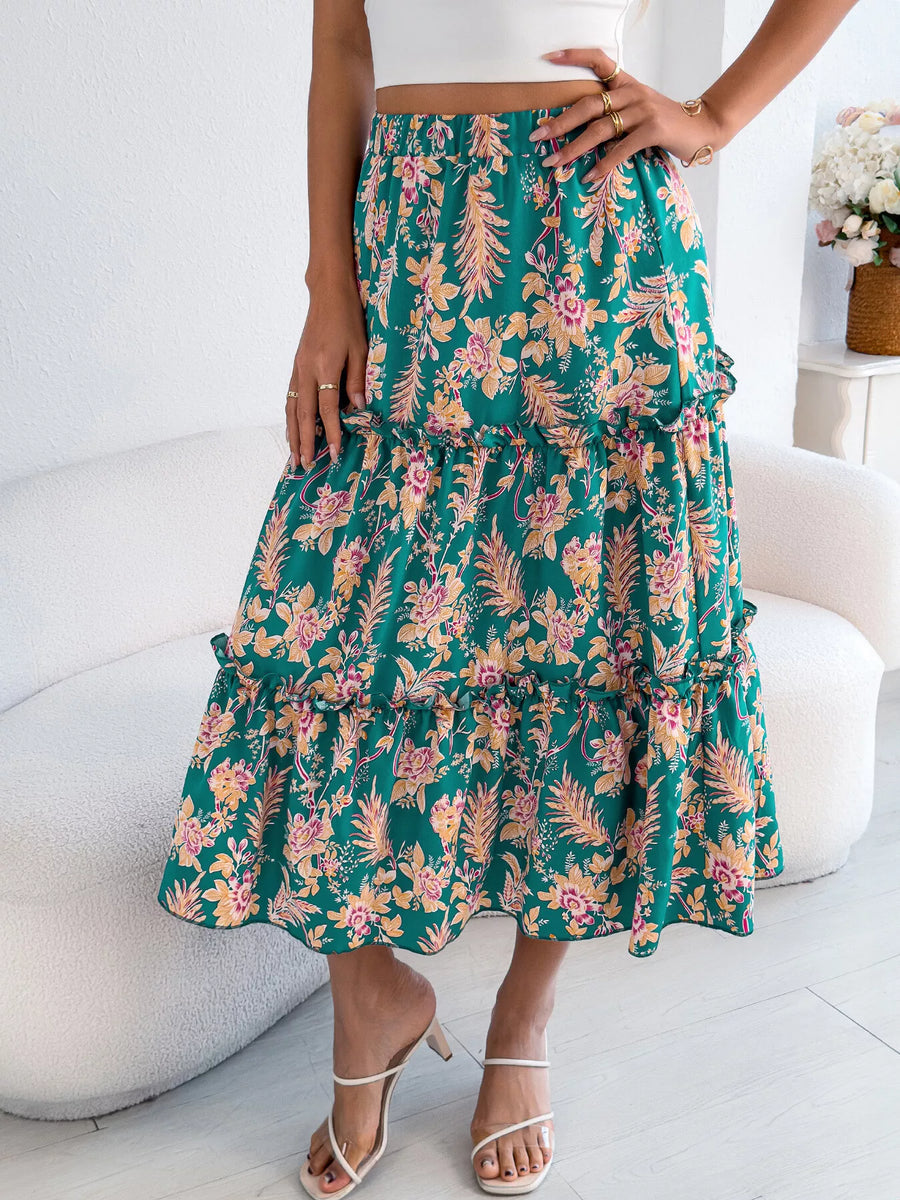 Person wearing a green floral skirt sitting on a white chair.