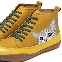 Yellow high-top sneakers with green laces and a cat peeking out from the side.