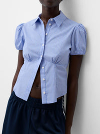 Person wearing a blue puffed-sleeve shirt against a plain background