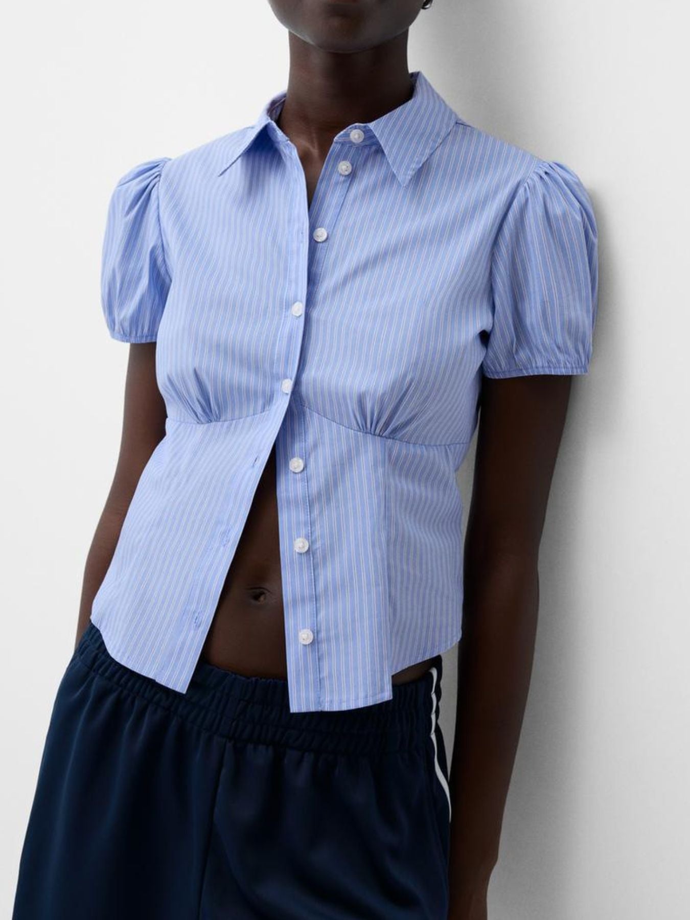Person wearing a blue puffed-sleeve shirt against a plain background
