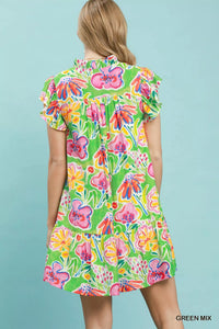Woman wearing a colorful floral dress against a light blue background