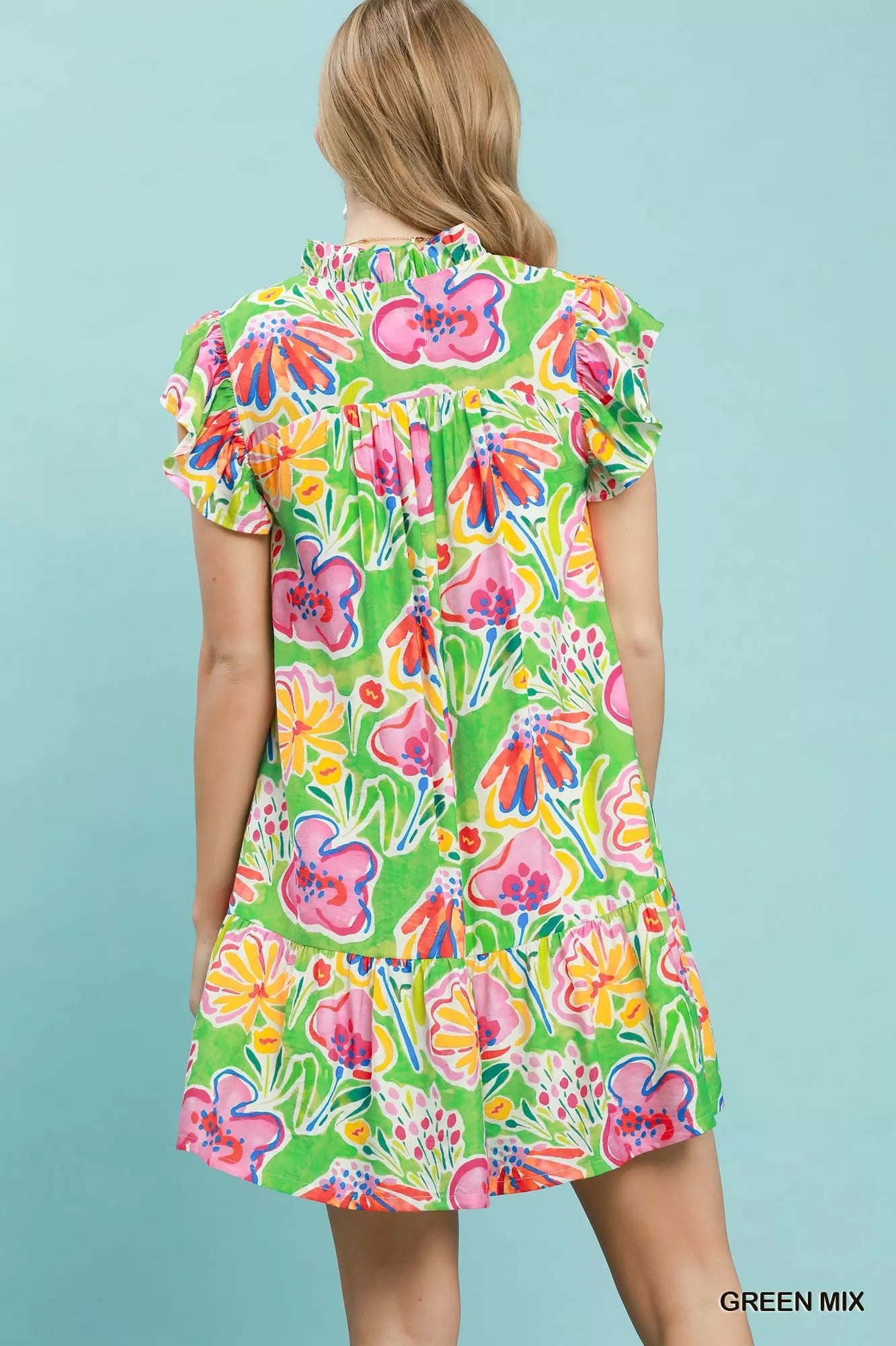 Woman wearing a colorful floral dress against a light blue background