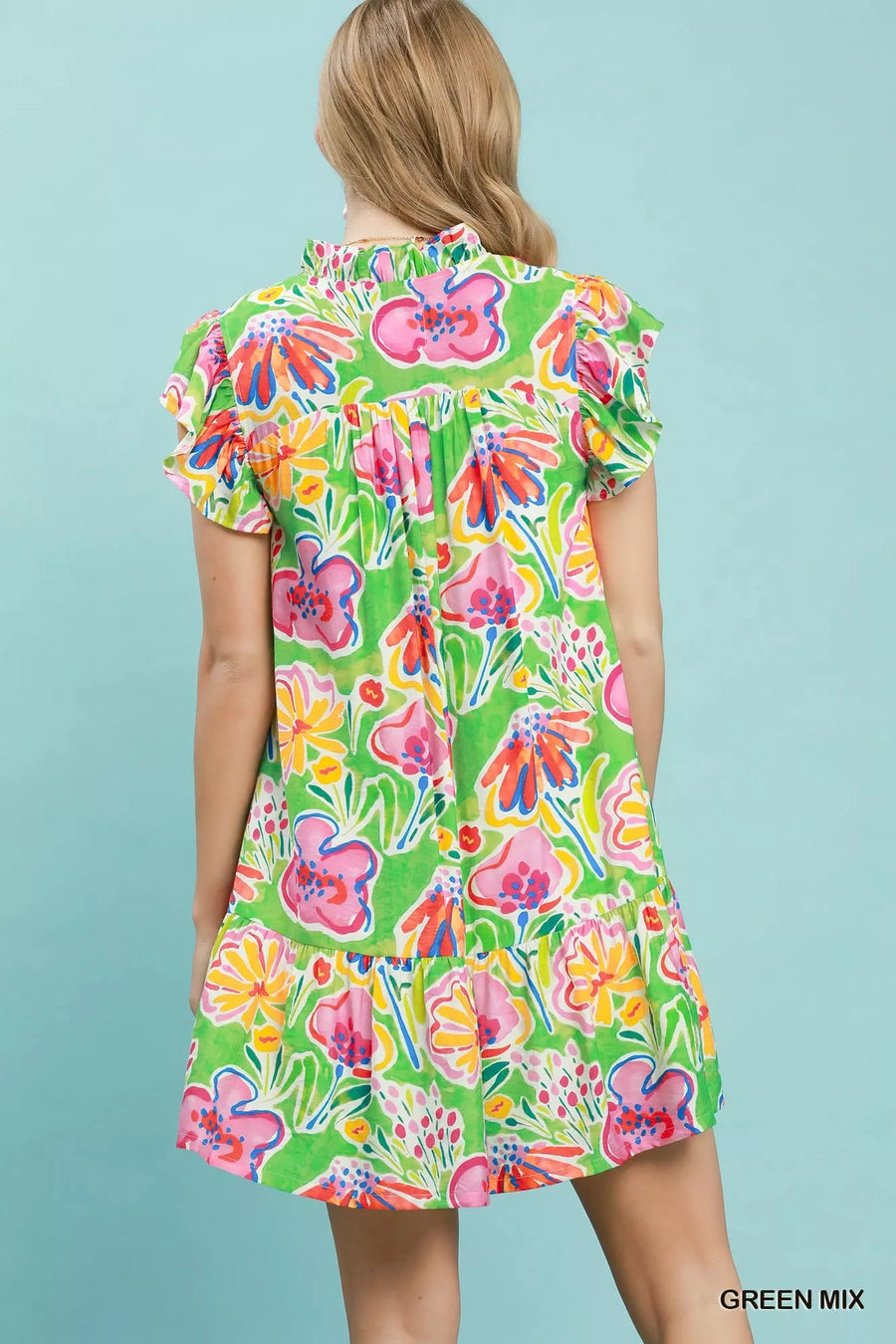 Woman wearing a colorful floral dress against a light blue background