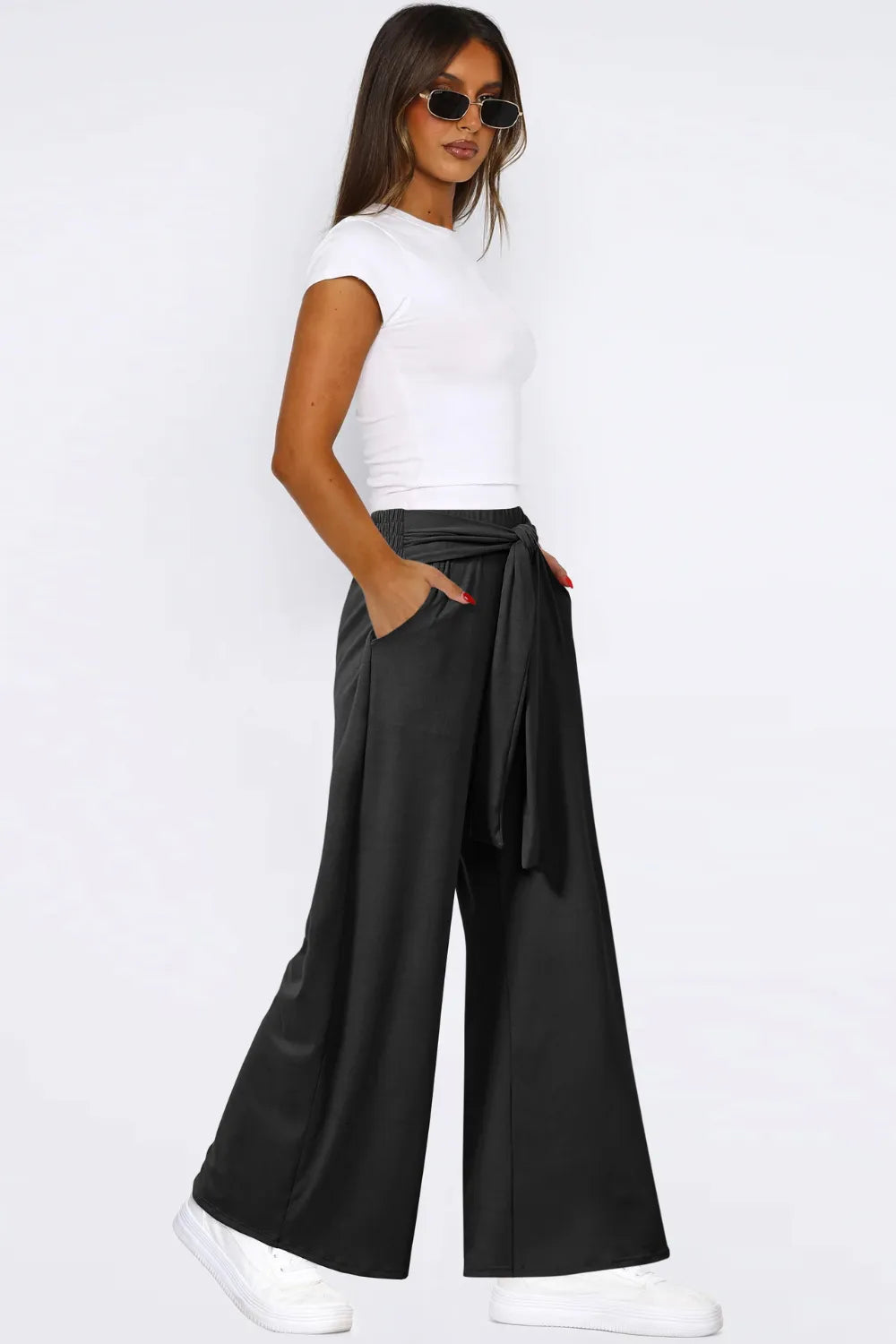 Woman wearing a white top and black wide-leg pants on a white background