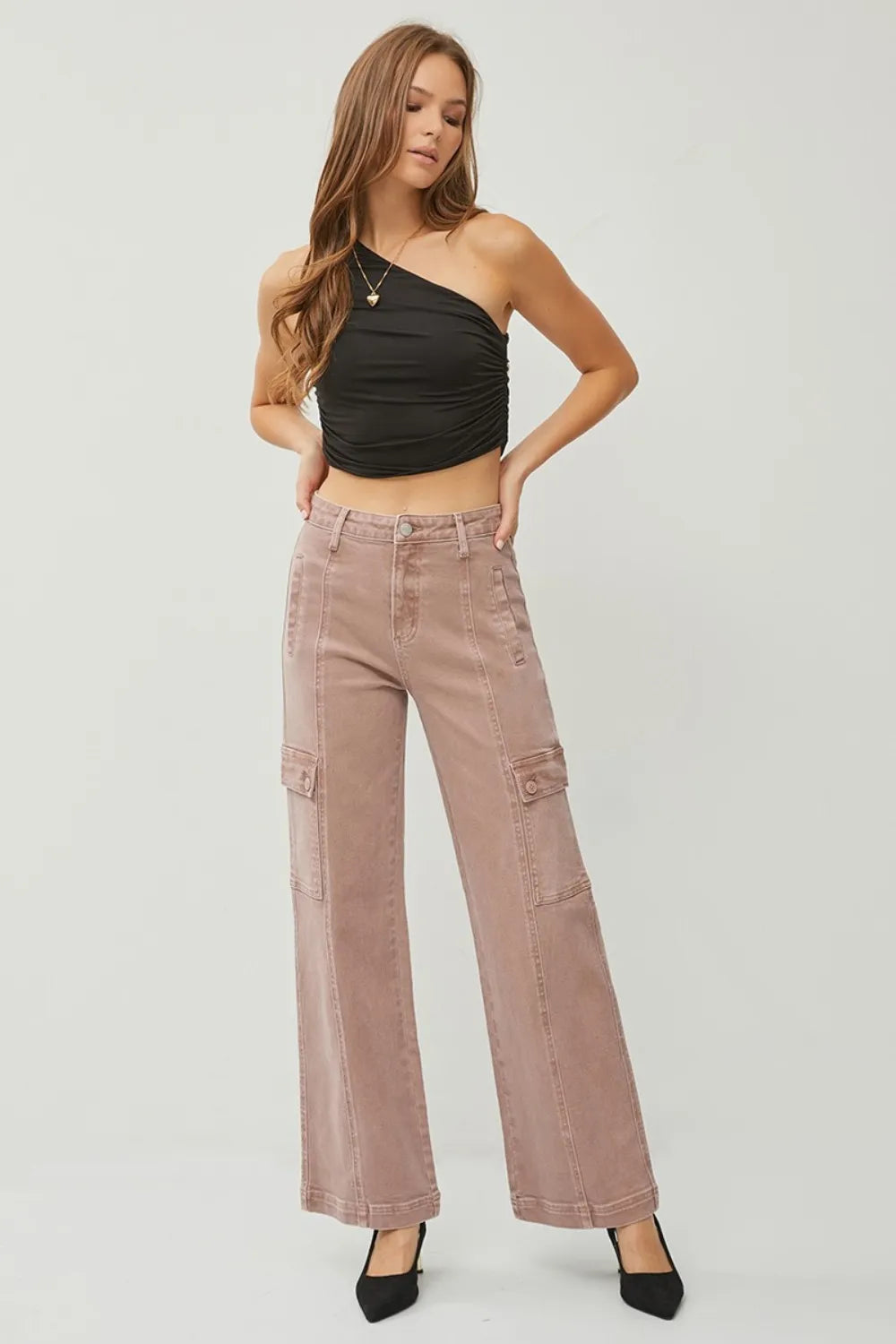 Woman wearing a black halter top and pink cargo pants on a white background