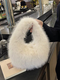 White fluffy handbag held by a person in a bar setting