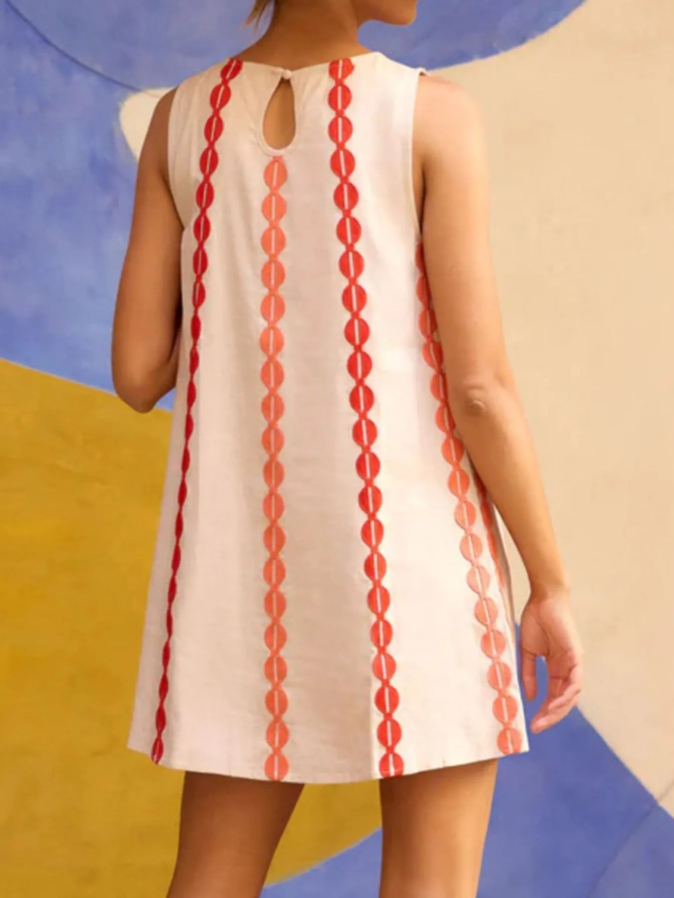 White dress with red pattern on a colorful abstract background