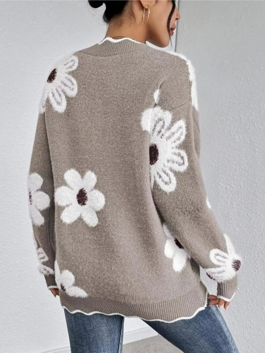 Person wearing a brown sweater with white floral patterns on a plain background