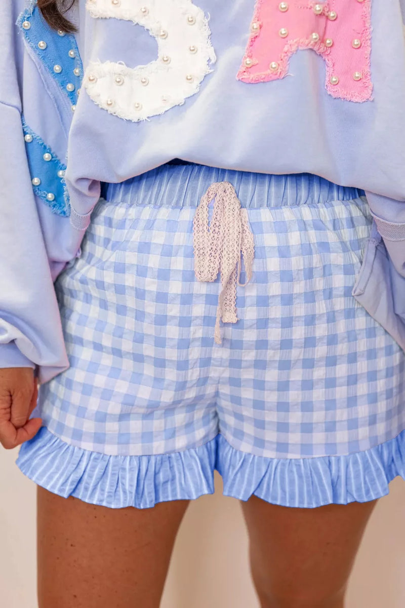 Person wearing a light blue checkered skirt with ruffled edges and a colorful top.