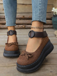 Brown platform shoes with black soles worn by a person on a wooden floor.