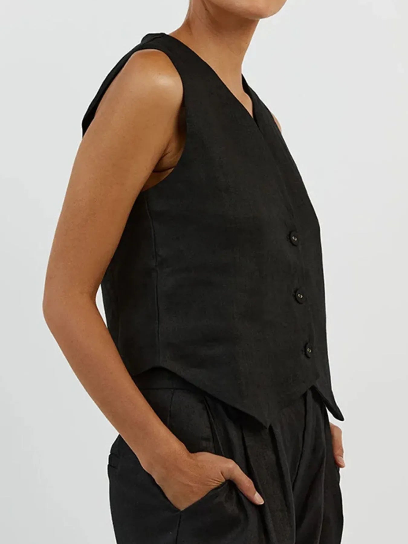 Person wearing a black vest and pants on a plain background