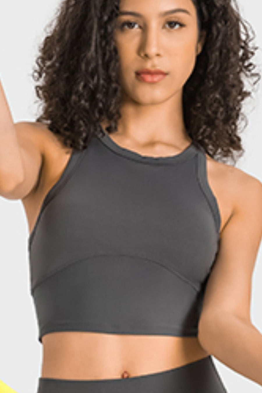 Woman wearing a gray sports bra and leggings on a white background