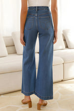 Person wearing blue jeans standing in a room with a white couch.