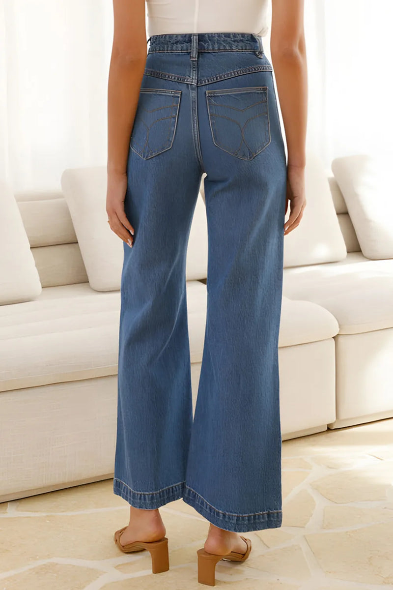 Person wearing blue jeans standing in a room with a white couch.