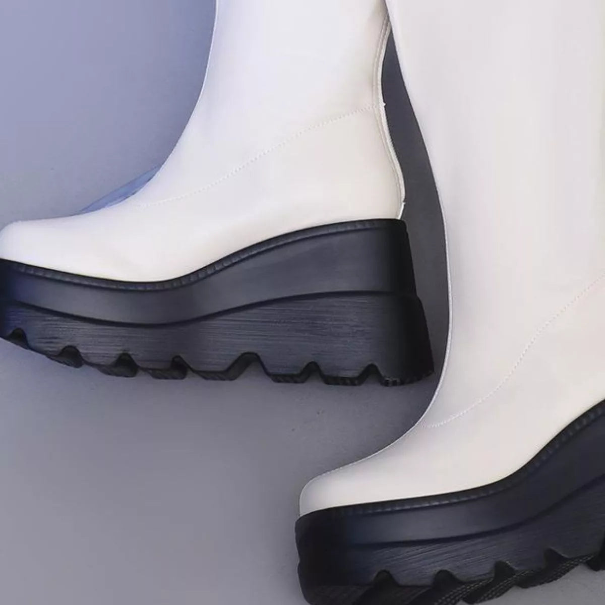 White boots with black soles on a light gray background