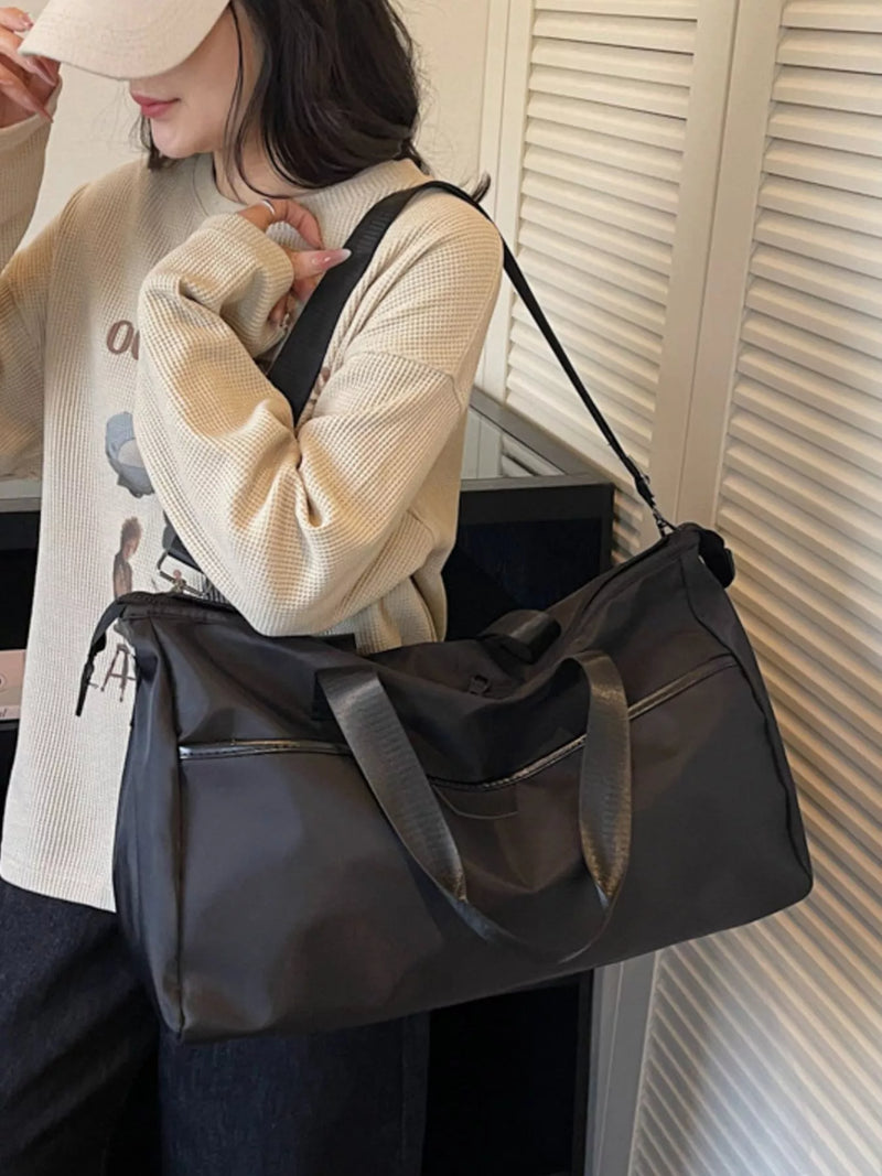 Person holding a black duffel bag with a neutral background