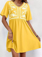 Yellow dress with white floral embroidery on a white background