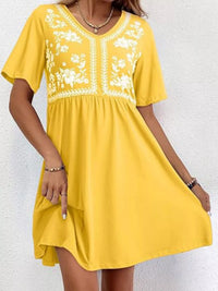 Yellow dress with white floral embroidery on a white background