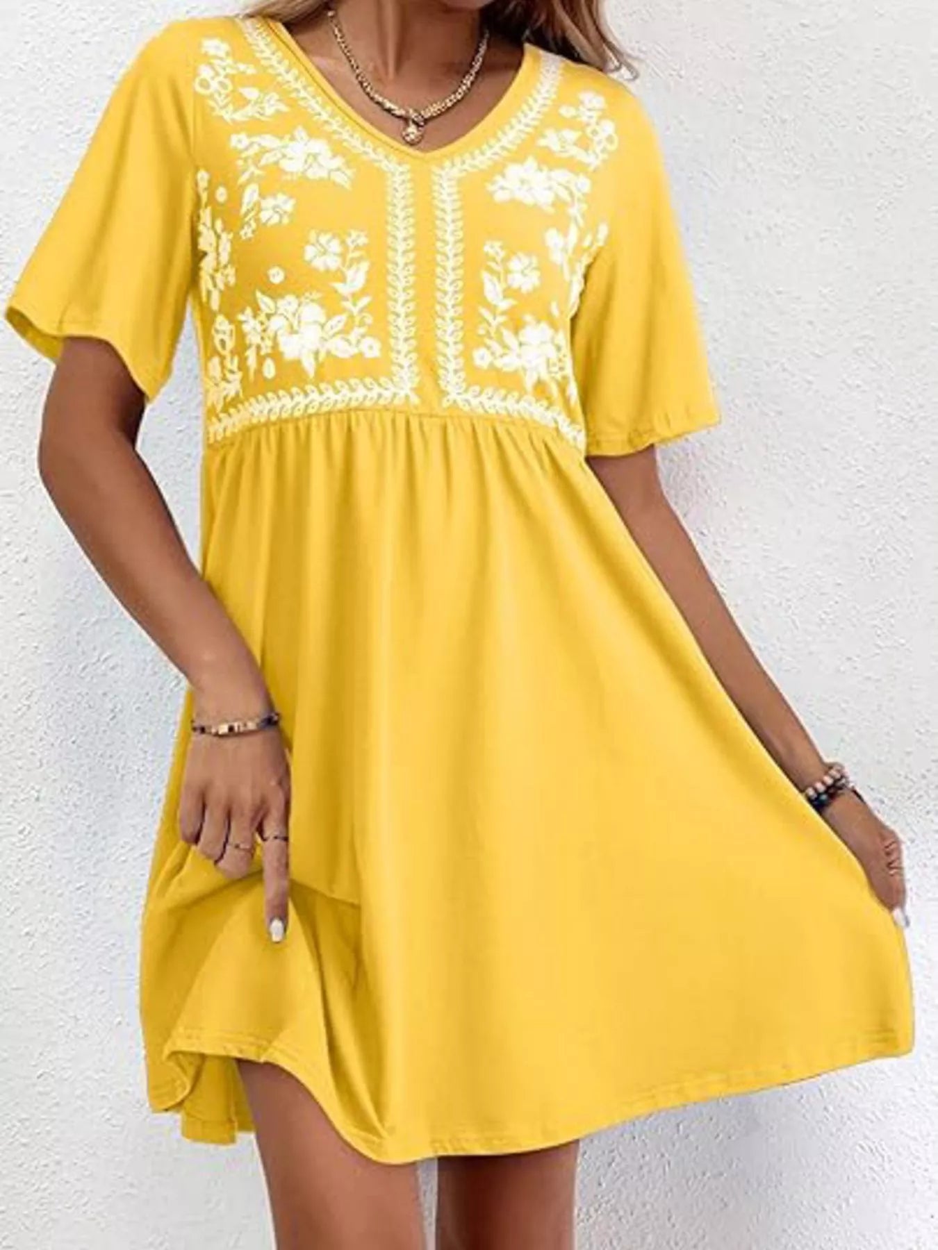 Yellow dress with white floral embroidery on a white background