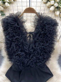 Black ruffled garment on a hanger against a floral background
