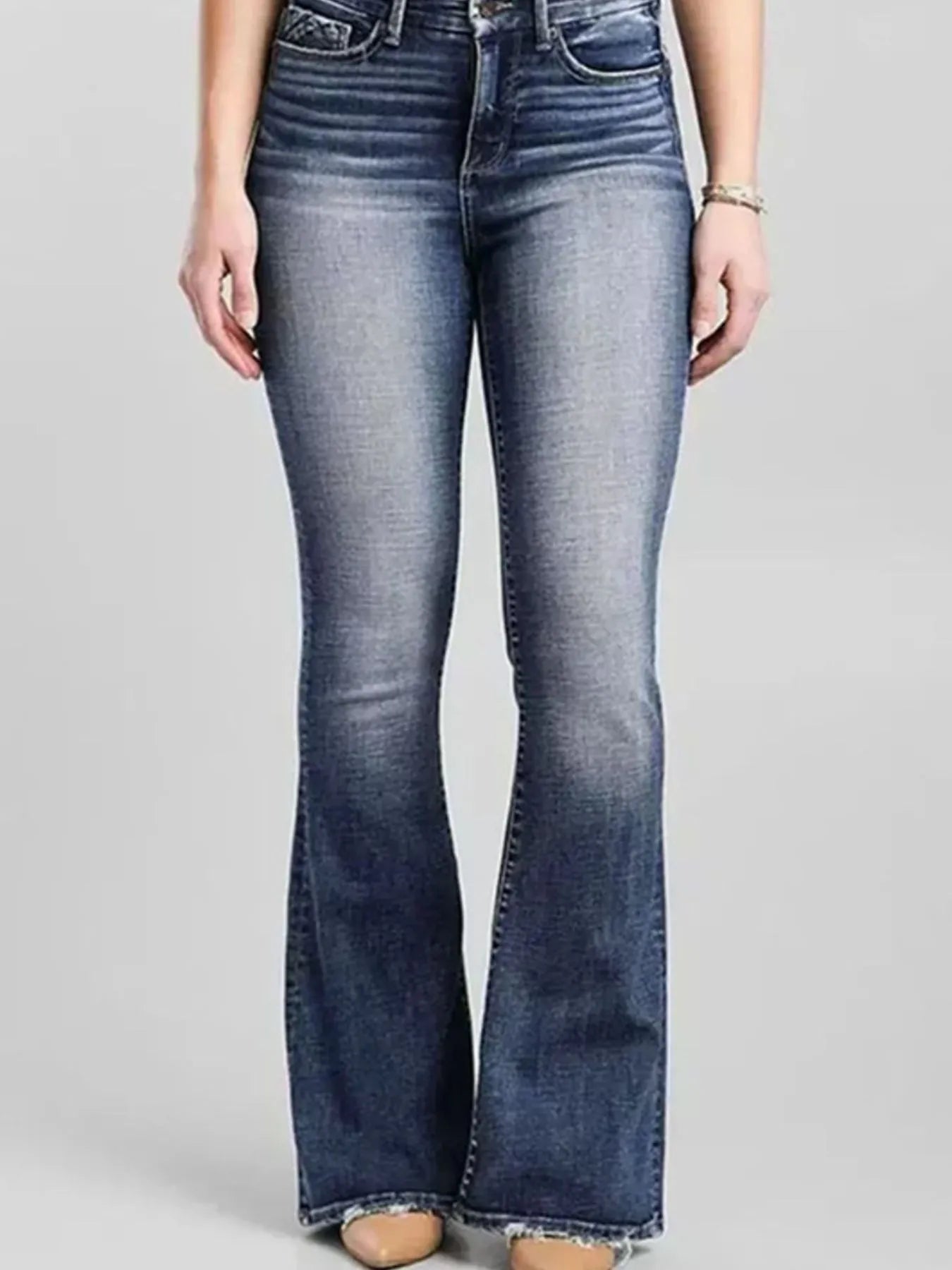 Flared jeans worn by a person on a plain background