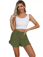 Woman wearing a white tank top and green shorts on a white background