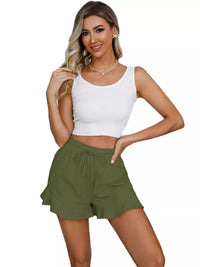 Woman wearing a white tank top and green shorts on a white background