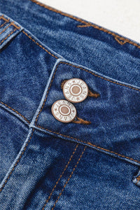 Close-up of blue denim fabric with metal buttons on a white background